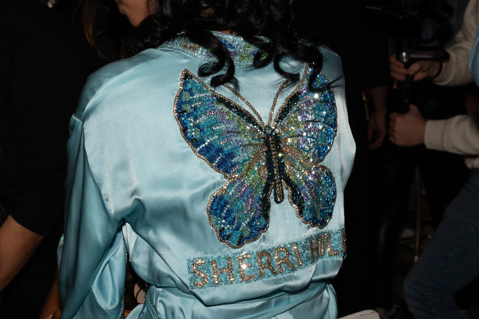 The butterfly embroidered on the back of a blue satin Sherri Hill robe