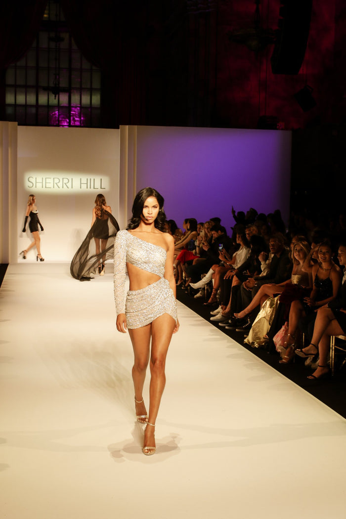 Model Daiane Sodre in the silver beaded one-shoulder cutout mini on the runway