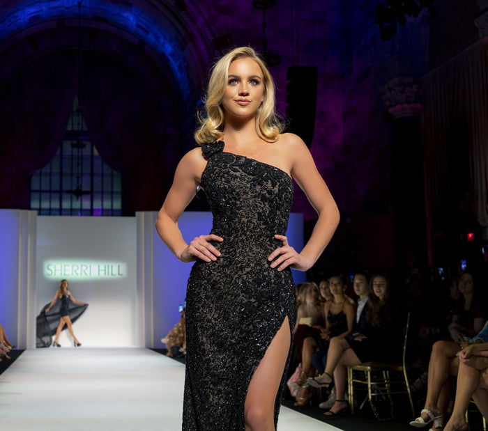 Model Emma Brooks in the black one-shoulder beaded gown with a slit, seen from the front row