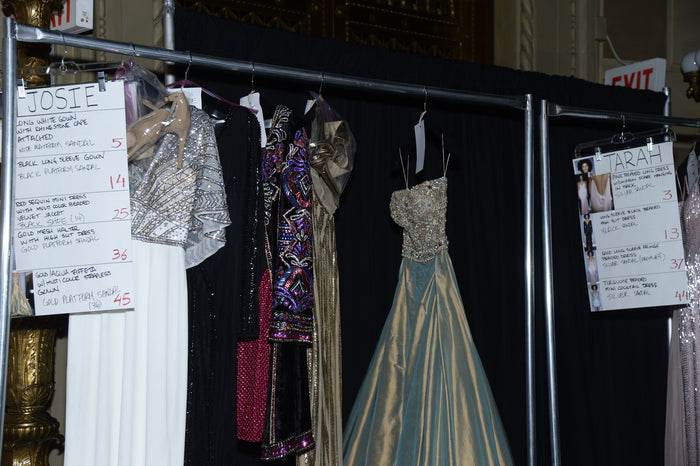 Gowns on the rack with their look cards backstage
