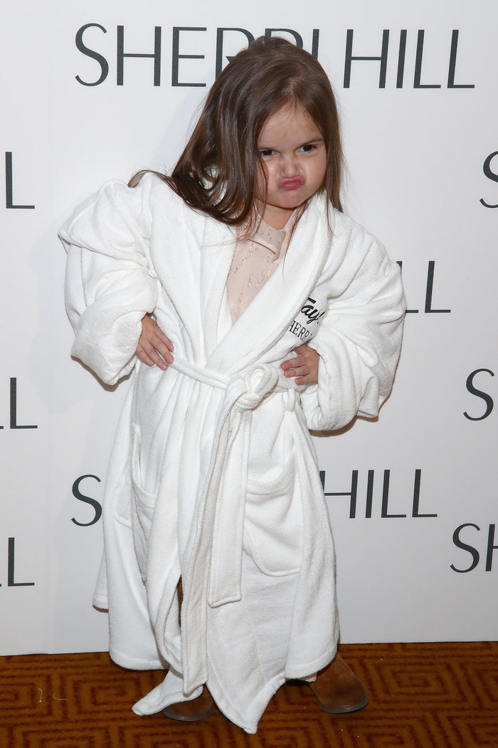 Model Taylen Biggs in a white Sherri Hill robe on the step-and-repeat