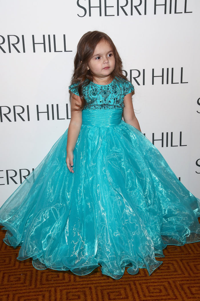 Model Taylen Biggs in a teal ballgown on the step-and-repeat