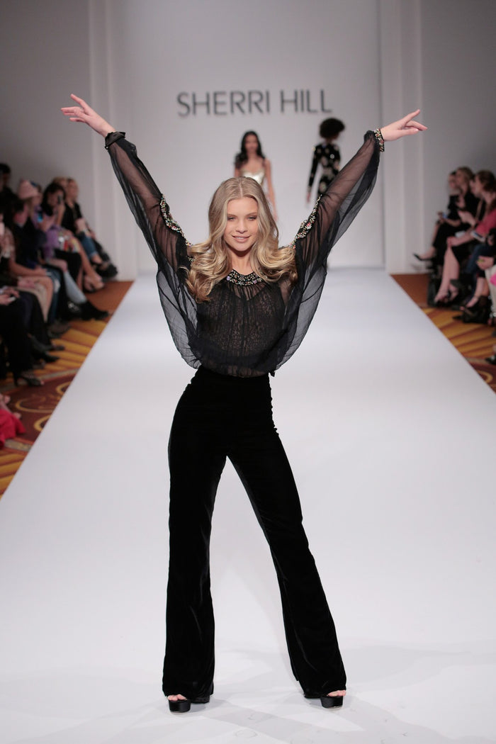 Model Josie Canseco in a sheer black top and black pants on the runway