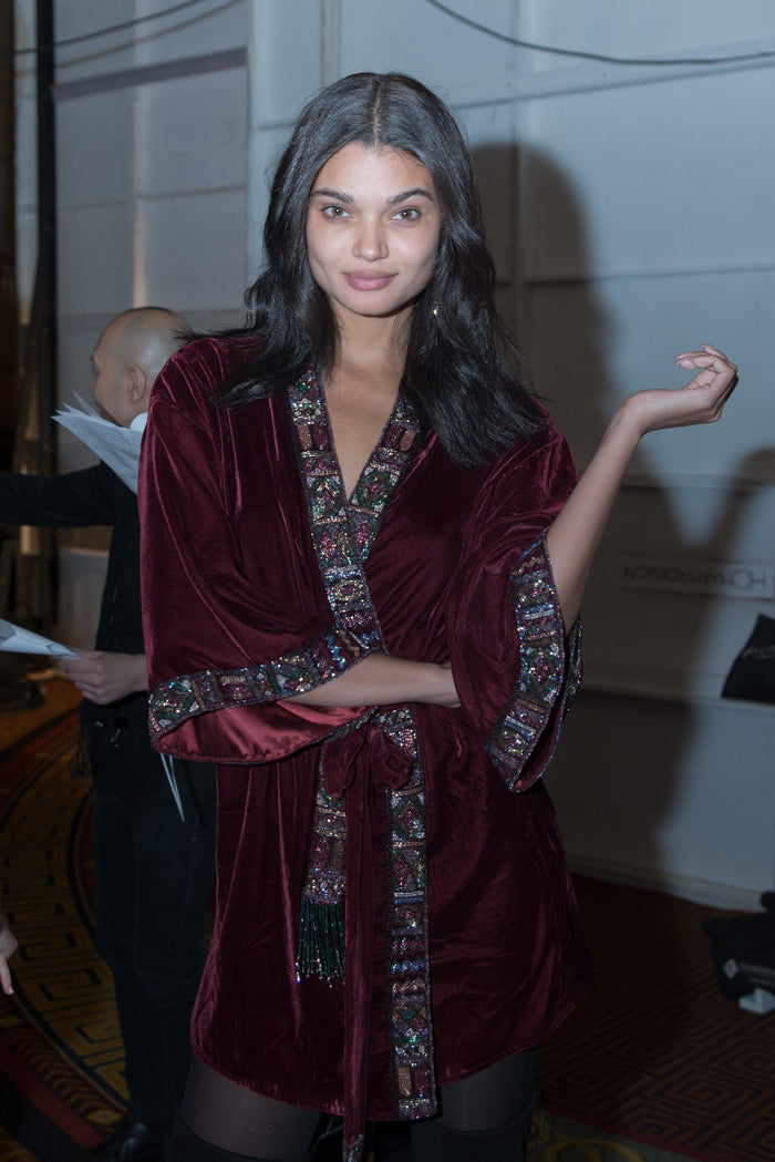 A model in a burgundy Sherri Hill robe backstage before the show