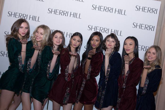 Models in green and burgundy velvet robes on the step-and-repeat before the show