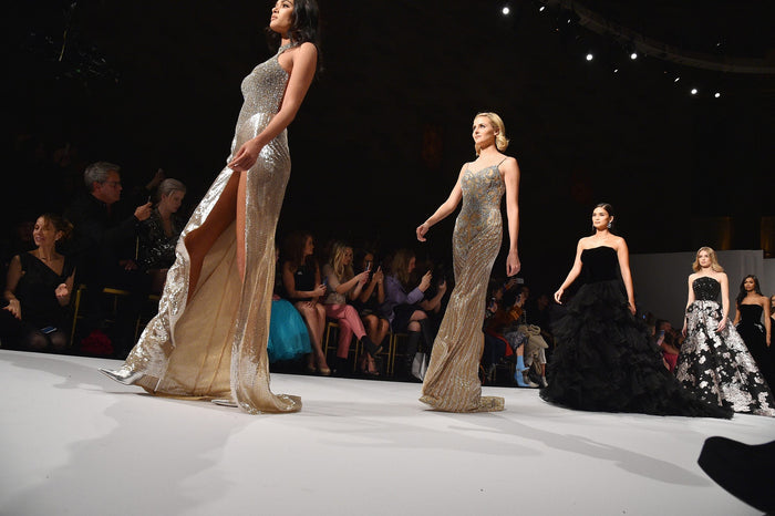 Gold and black gowns on the runway, seen from the front row