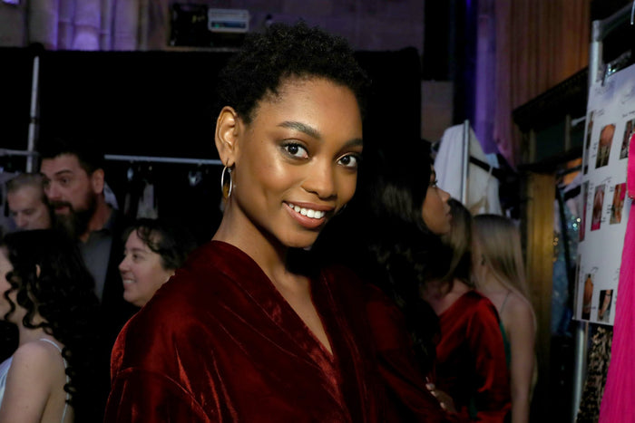 A model in a burgundy velvet robe backstage before the show