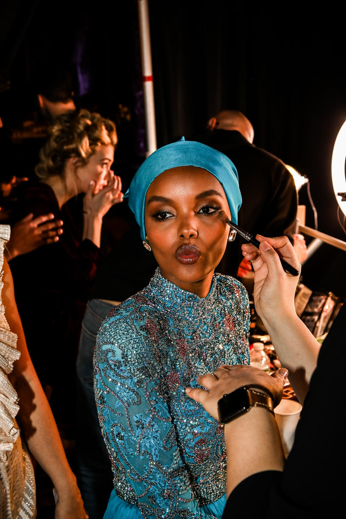 Model Halima Aden in the turquoise beaded gown has her makeup finished backstage