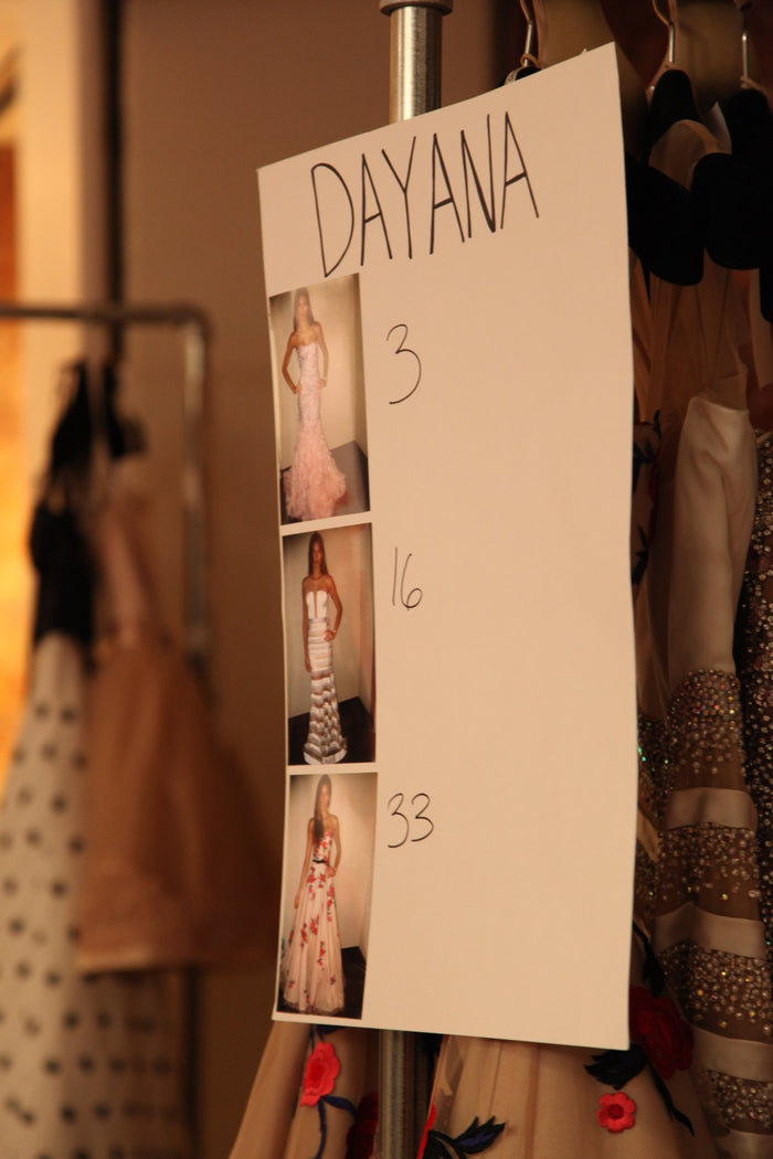 A model's rack backstage, tagged with her exits