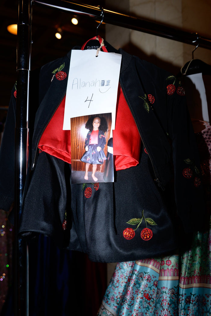 The cherry-embroidered black bomber jacket from look 3 on the rack with its look card