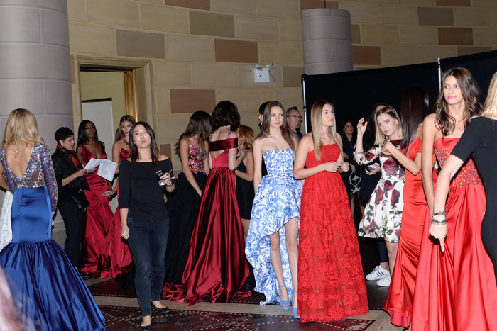 Models in red, blue and white gowns line up backstage at Gotham Hall
