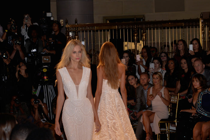 The white beaded gowns on the runway, seen from the front row