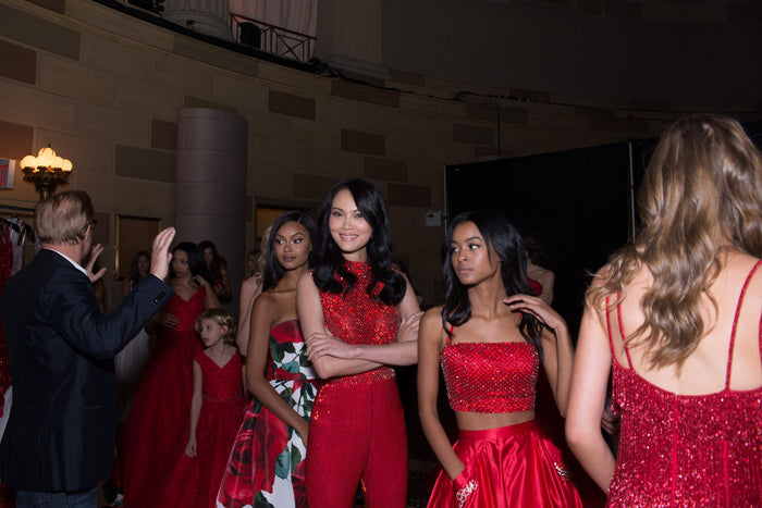 Models in red line up backstage before the show