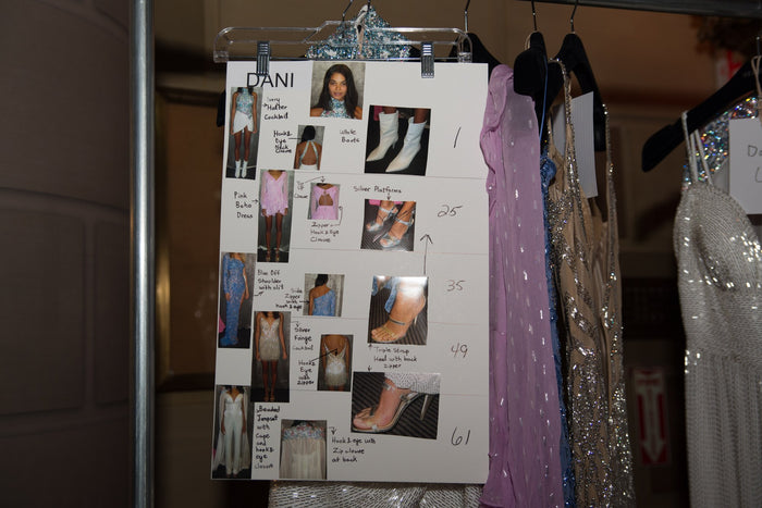 The look board backstage, with the gowns lined up on the rack behind it