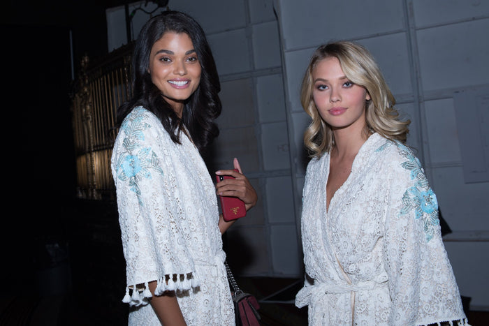Two models in white robes backstage at Gotham Hall