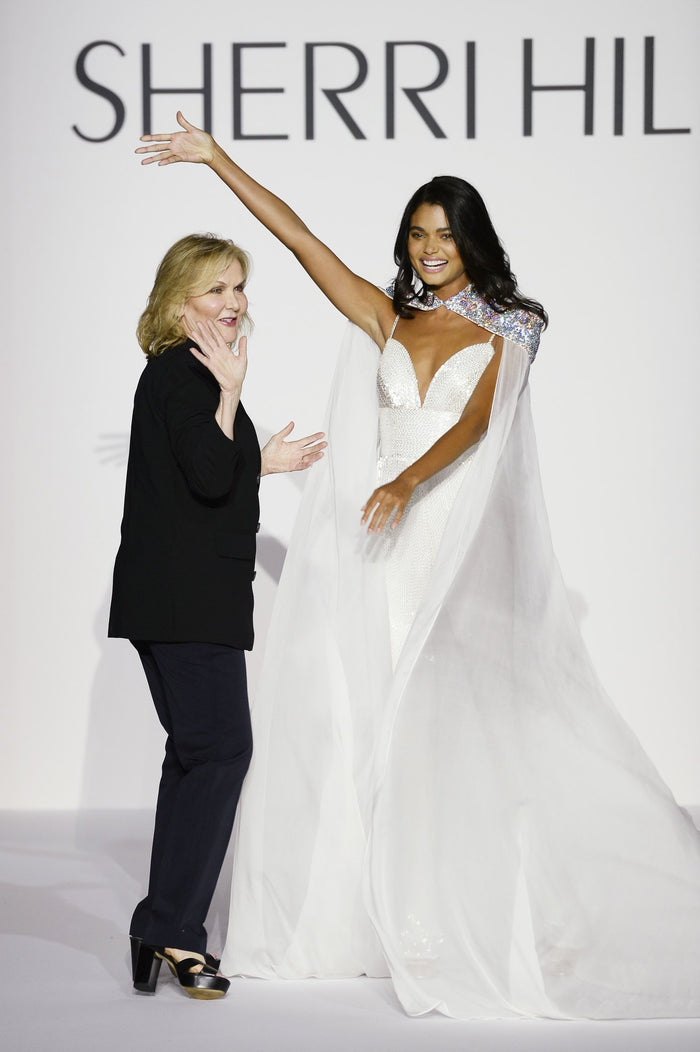 Sherri Hill takes her bow with model Daniela Braga in the finale look, a white jumpsuit with a beaded cape
