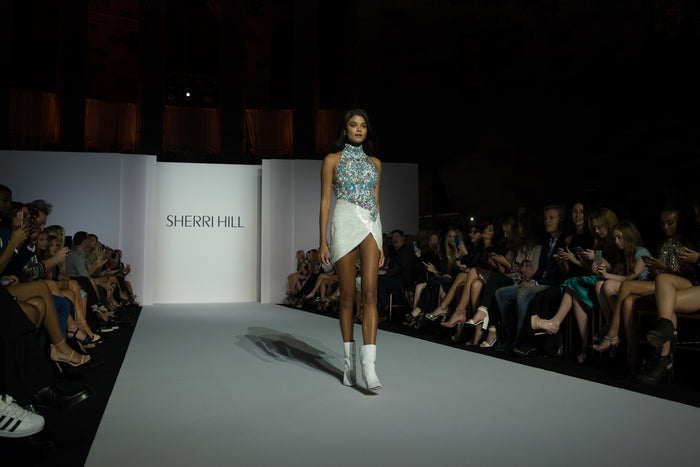 Model Daniela Braga opens the show in a white halter mini, seen from the front row