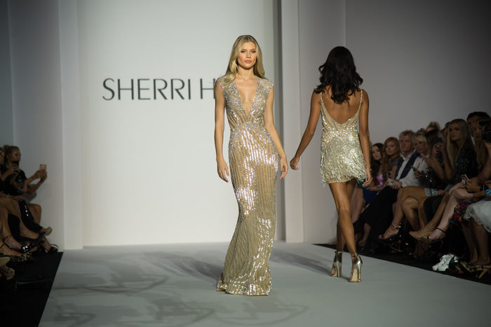 Model Josie Canseco in a gold beaded gown on the runway, with a gold fringe mini behind her