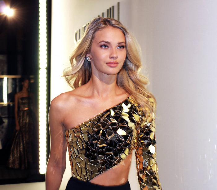 A gold mirrored one-shoulder top and black pants backstage