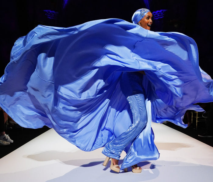 Model Halima Aden spins in a periwinkle satin cape gown on the runway