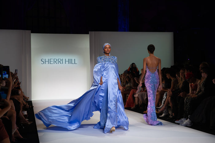 A periwinkle satin cape gown on the runway
