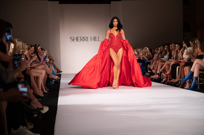 Model Daiane Sodre in the opening red look and its cape, seen from the front row